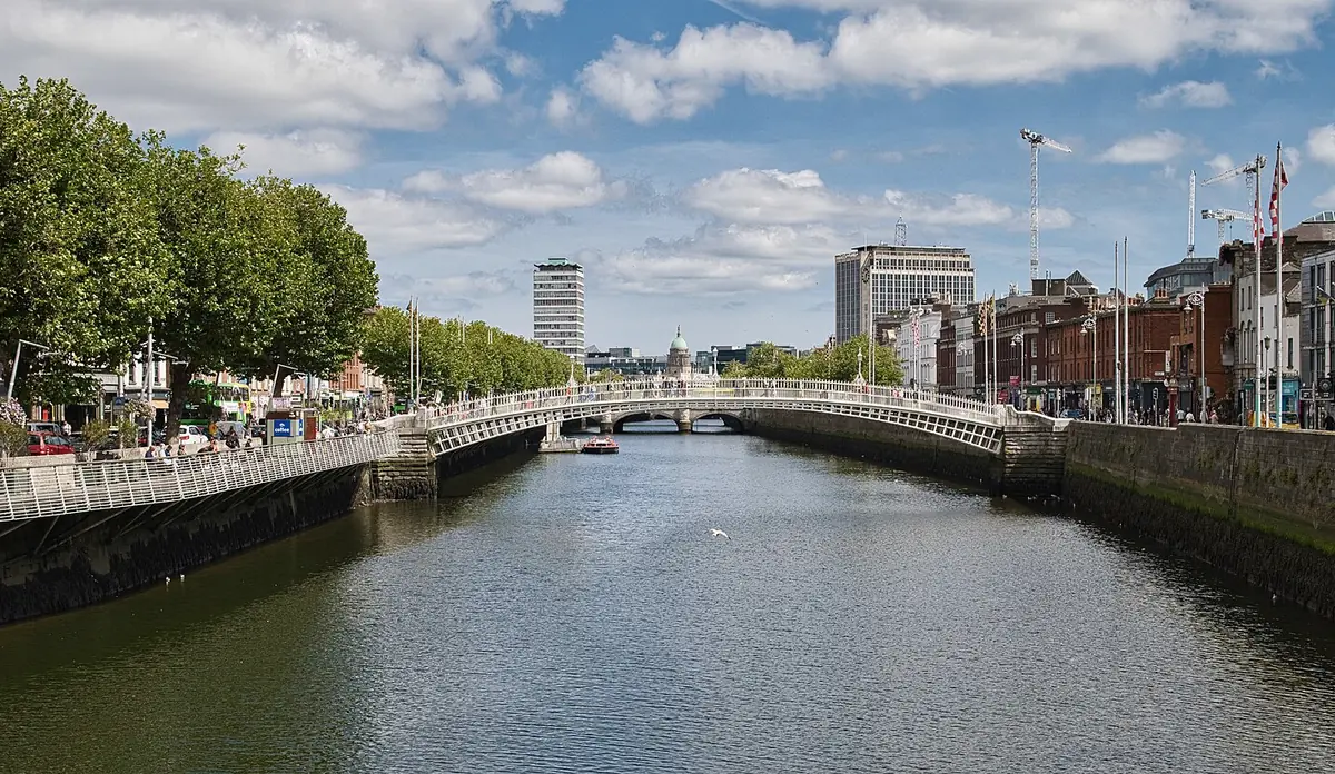 Il fiume Liffey a Dublino con l'arco bianco dell'Ha'penny Bridge e gli alberi sui lungofiume