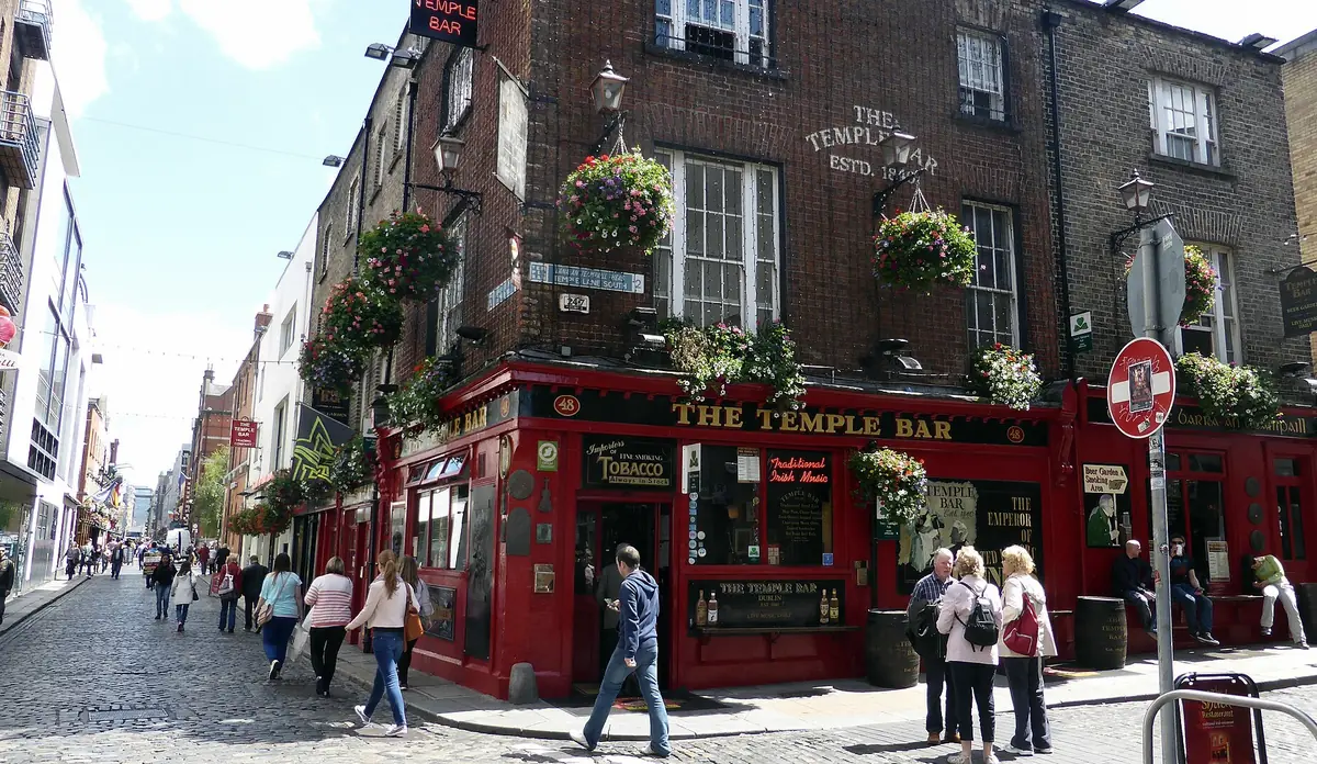 La facciata rossa del pub The Temple Bar, con cesti di fiori appesi, sulla via acciottolata di Temple Bar