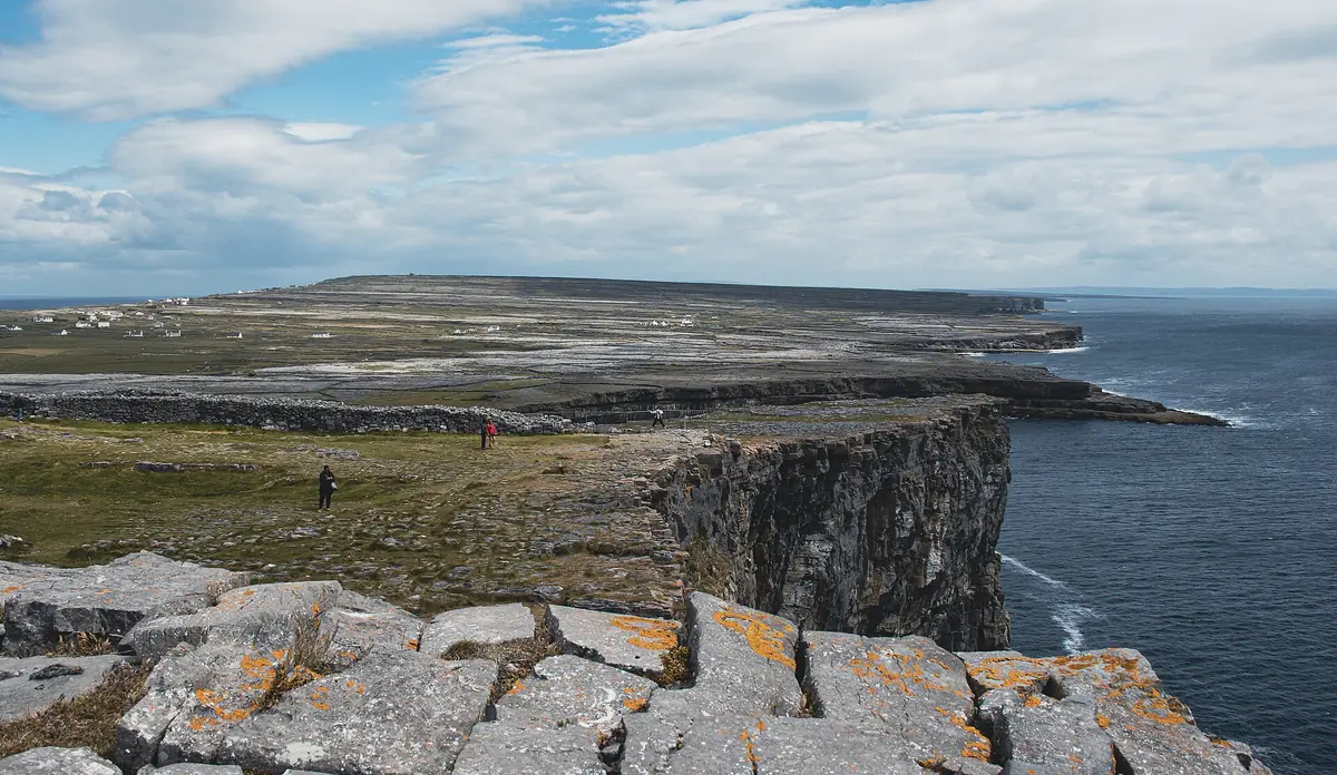 Scogliera a strapiombo sull'Atlantico a Dún Aonghasa, con il muro di pietra del forte e il tavolato calcareo di Inishmore
