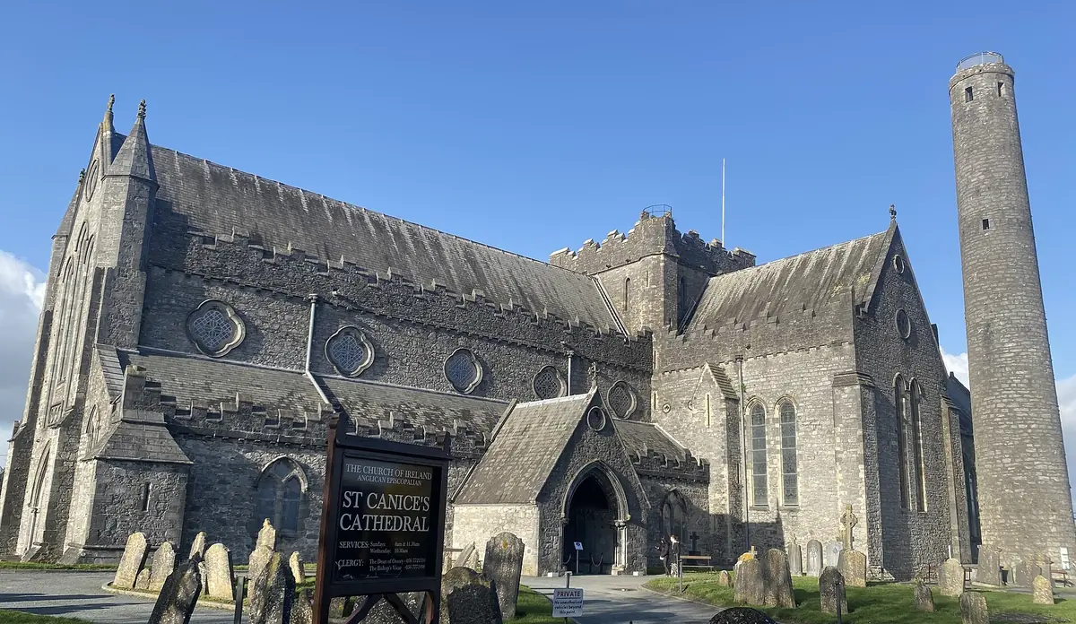St Canice's Cathedral a Kilkenny, in pietra grigia, con la torre circolare e il cimitero